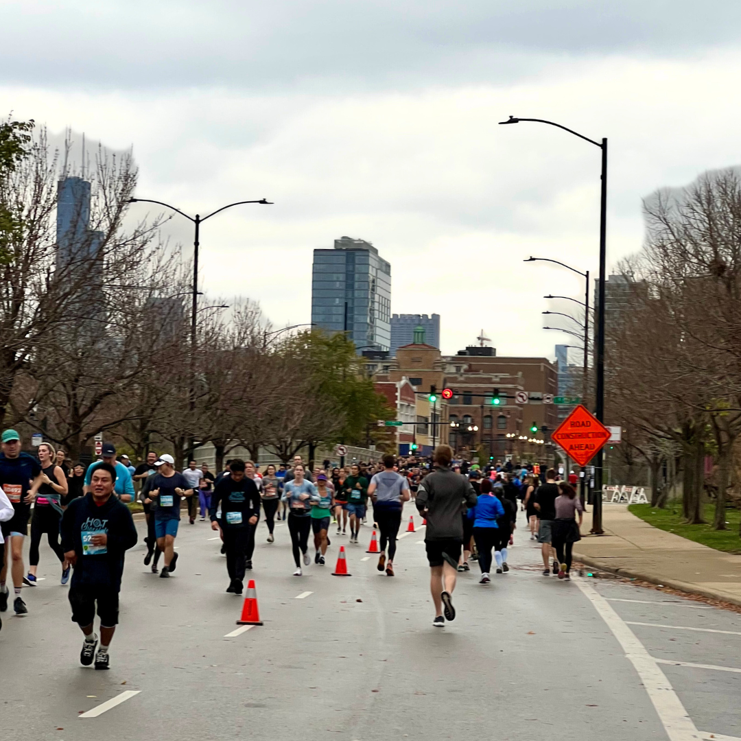 Runners crossing downtown Chicago streets during the 2025 Chicago Marathon with cheering crowds.